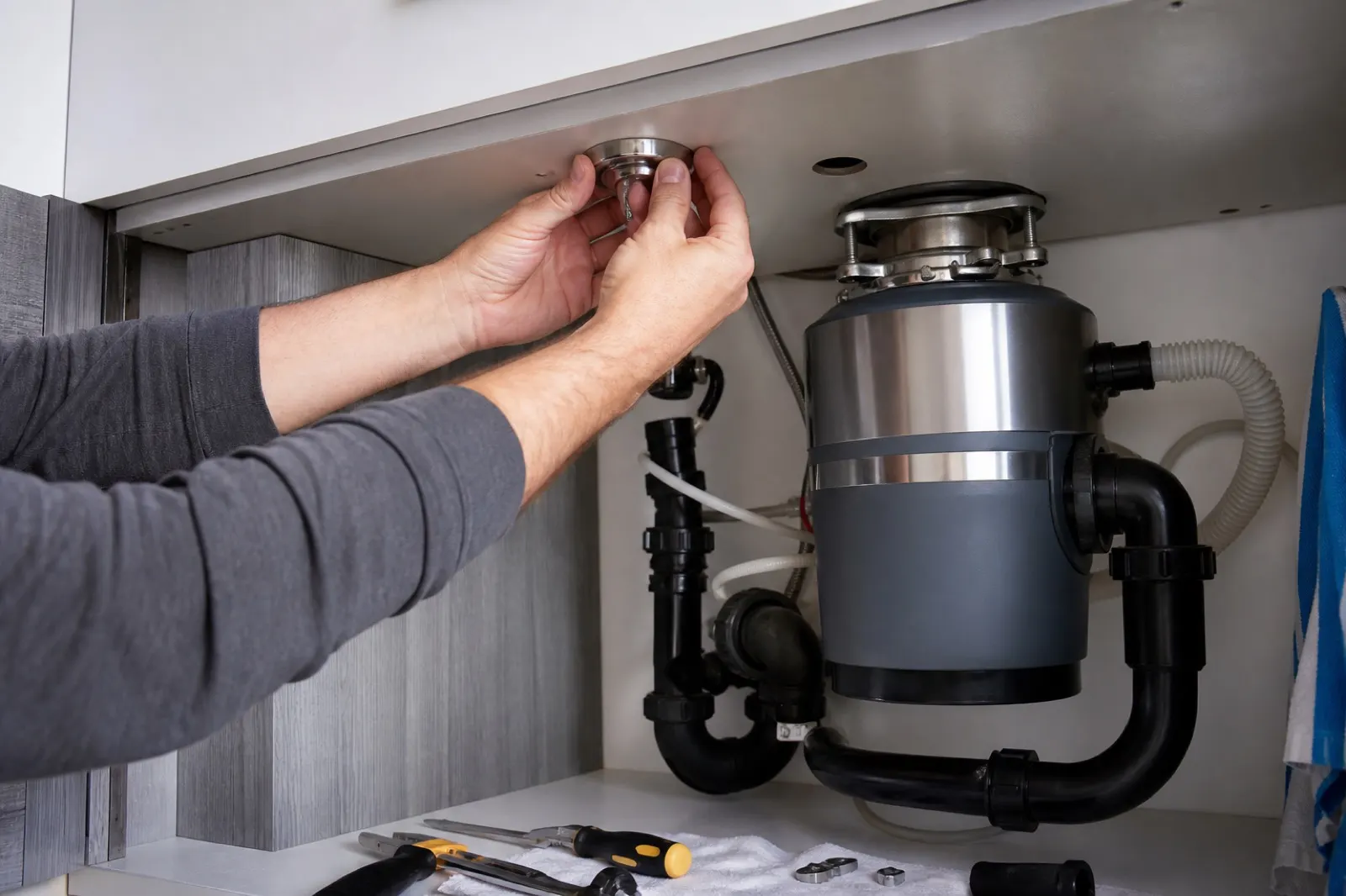 Handyman installing a garbage disposal air switch under a Miami kitchen sink