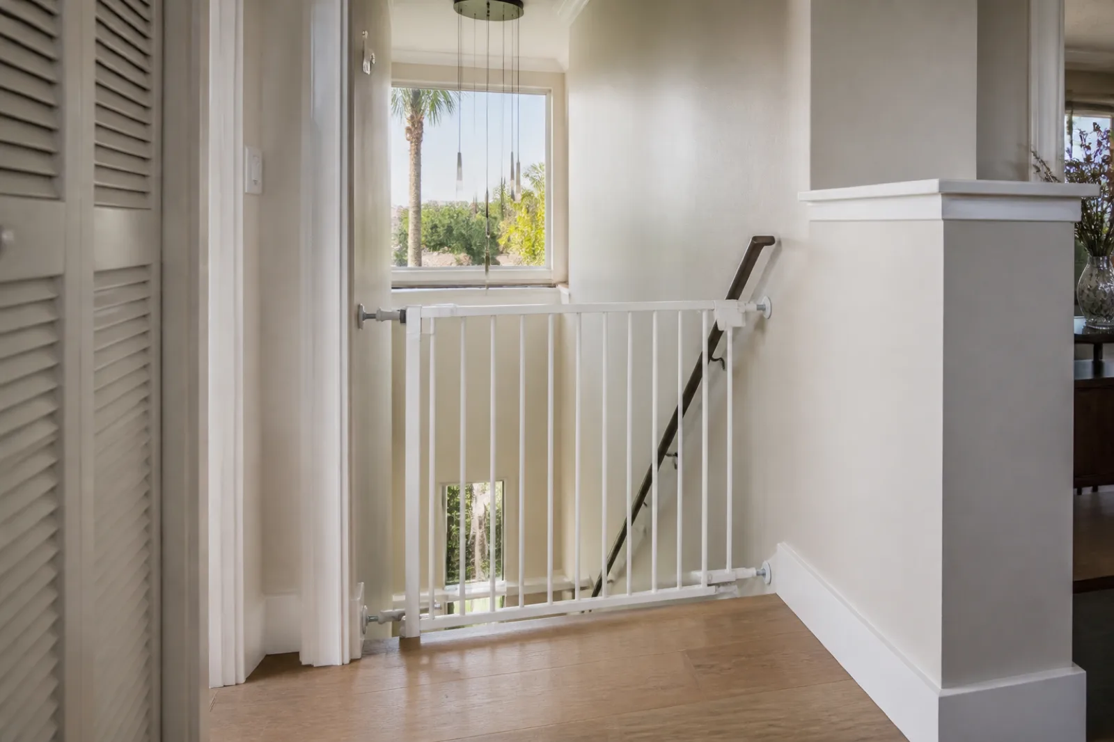 Hardware-mounted baby safety gate installed at the top of stairs in a Miami home