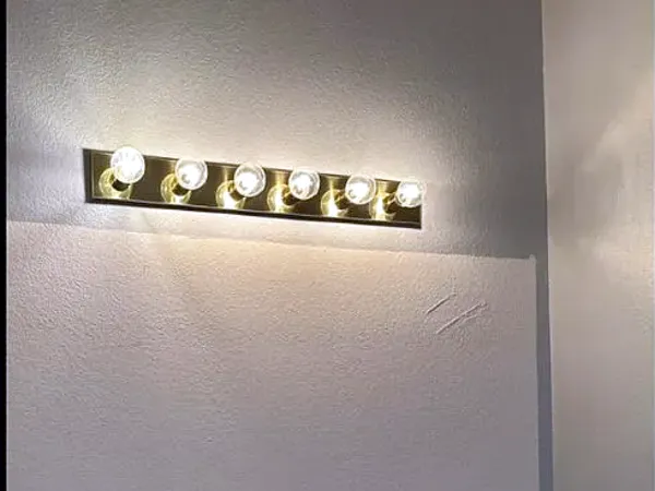 Before: bathroom wall with a vanity light and no mirror