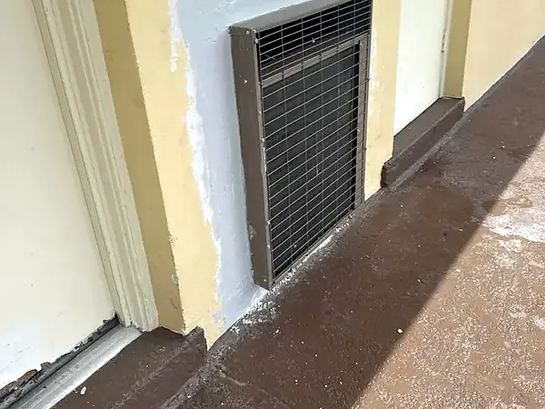 Before: stucco patched and primed around a wall AC unit